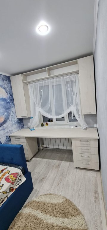 белый стол и навесные полки в детской комнате